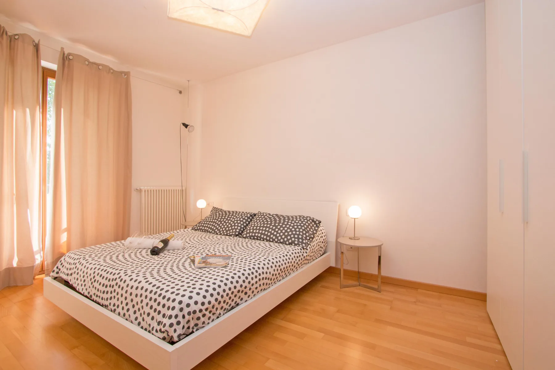 A bedroom with a low bed, patterned bedding, and curtained windows.
