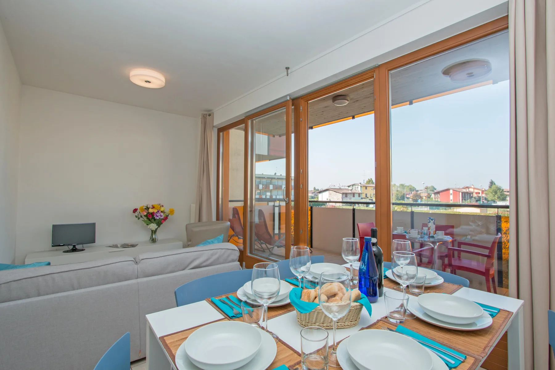 A bright living and dining room opens onto a balcony through large windows.