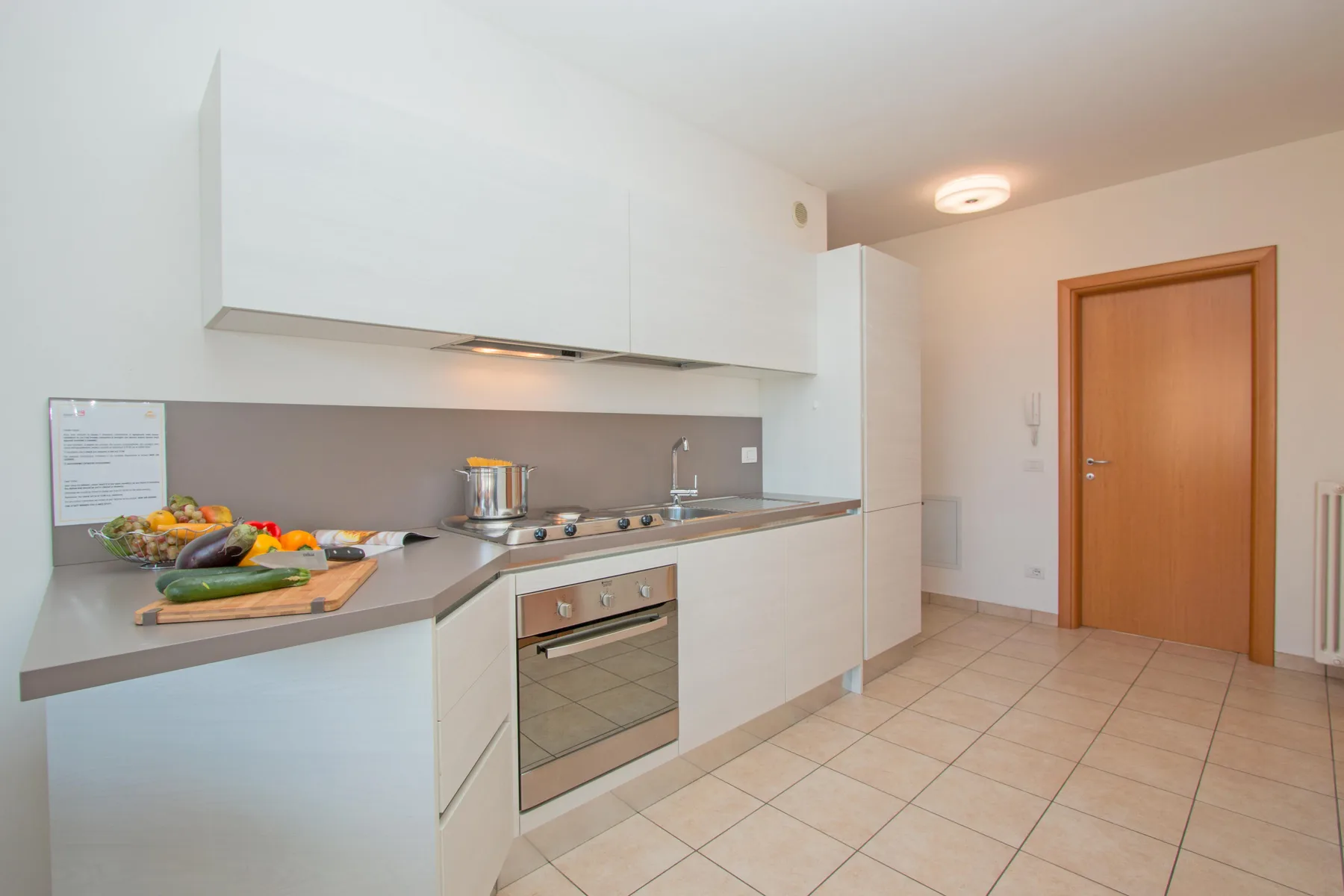 A bright kitchen with white cabinets, a countertop, and a built-in oven.