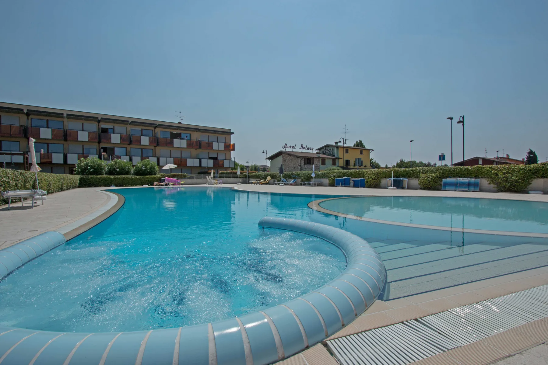 An outdoor swimming pool with curved edges sits beside a low building.