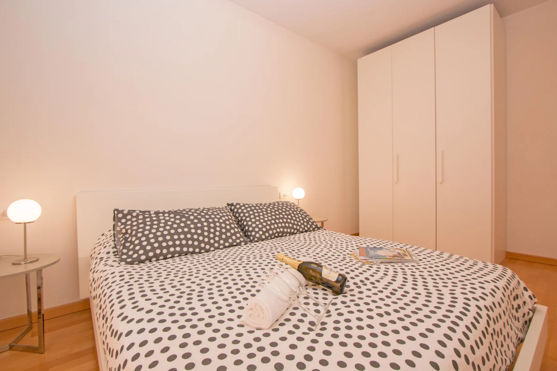 A bedroom with a patterned bedspread and a wardrobe beside the bed.