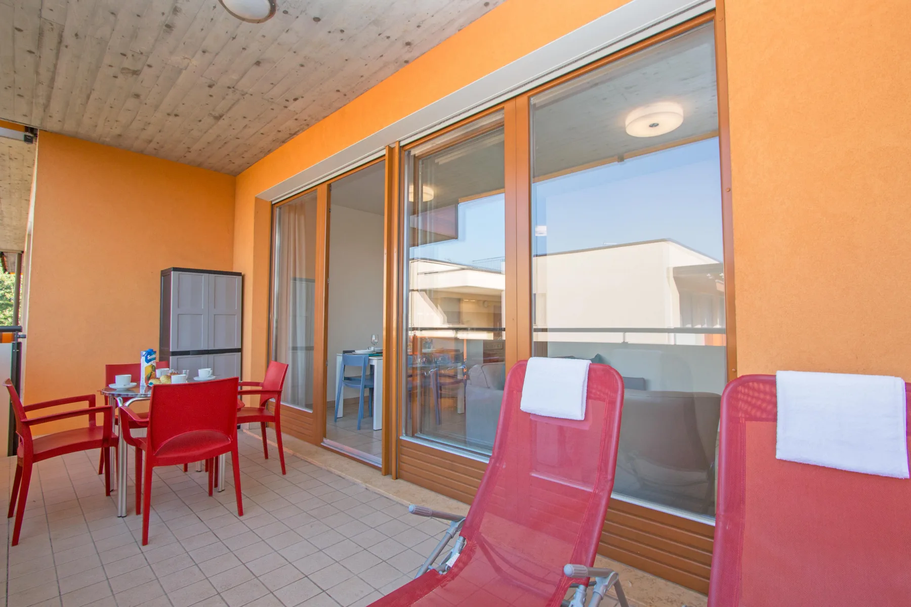 A bright patio with red seating and large glass doors.