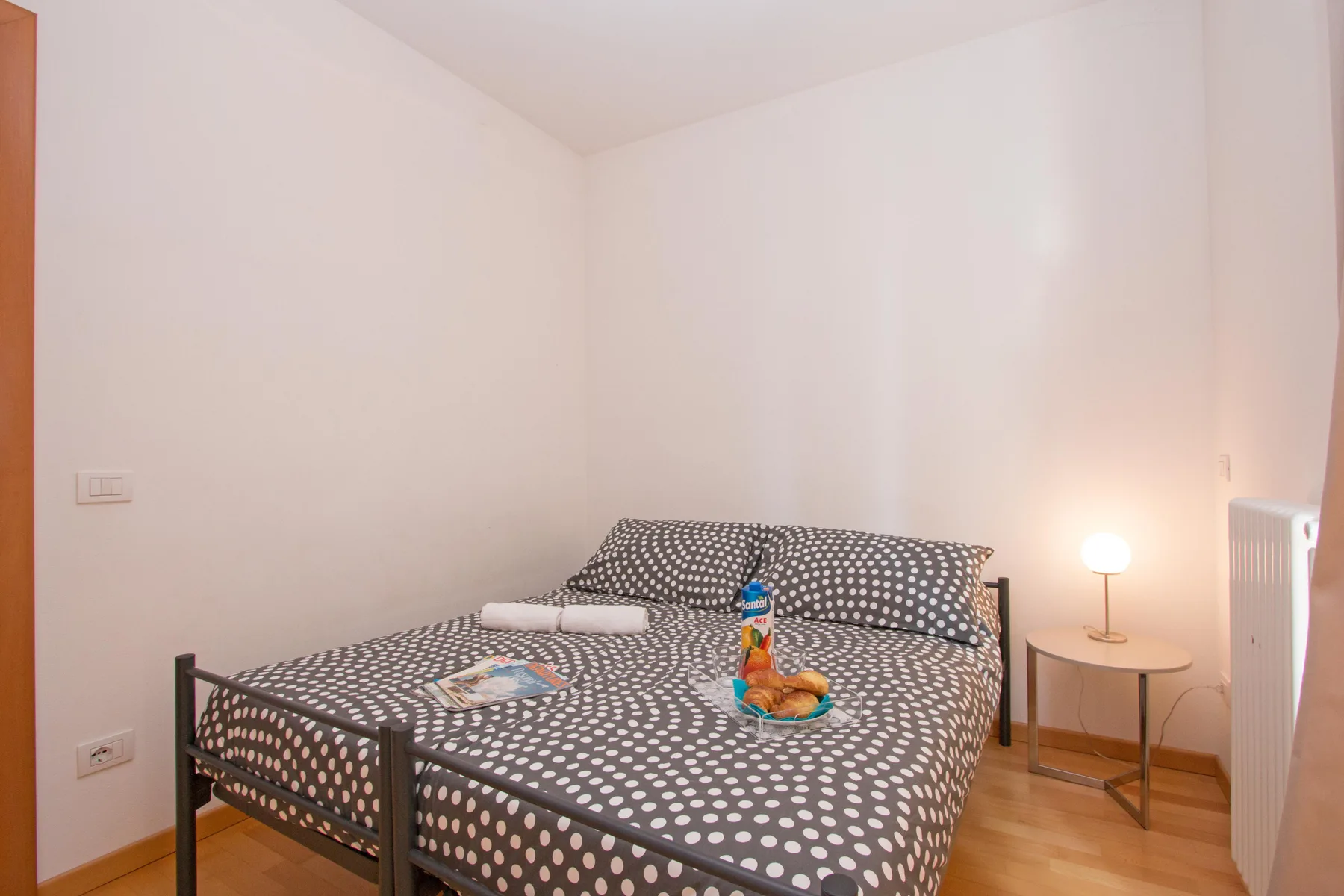 A bedroom with a bed covered in patterned bedding and a small bedside table.
