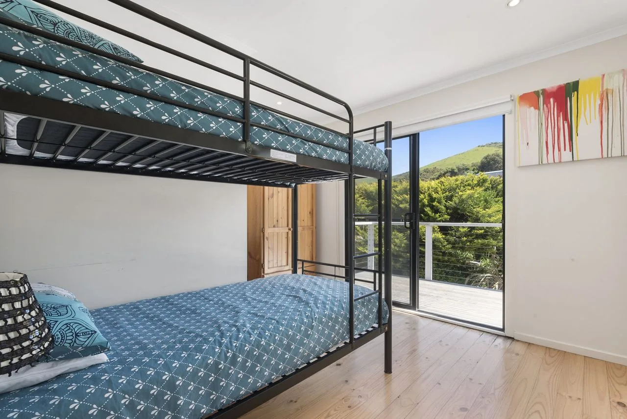 Un dormitorio con una litera junto a una puerta de cristal que da a un balcón.