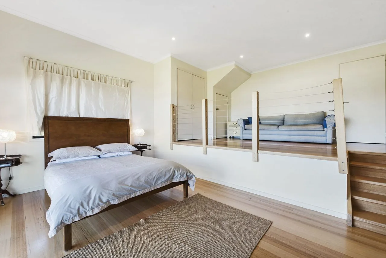Un dormitorio con una cama y una zona de estar elevada.