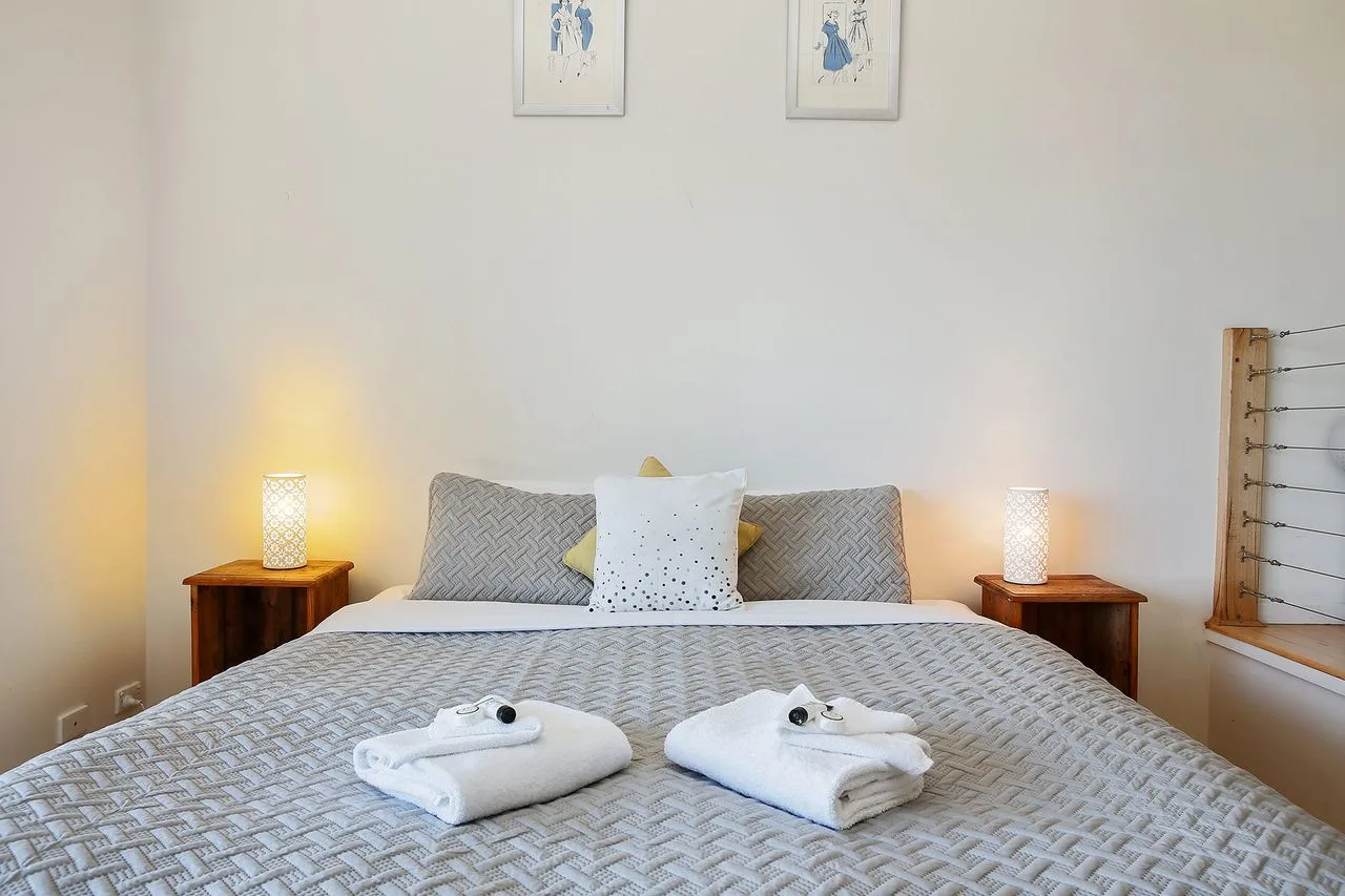 Un dormitorio con una cama bien arreglada y mesitas de noche a juego.