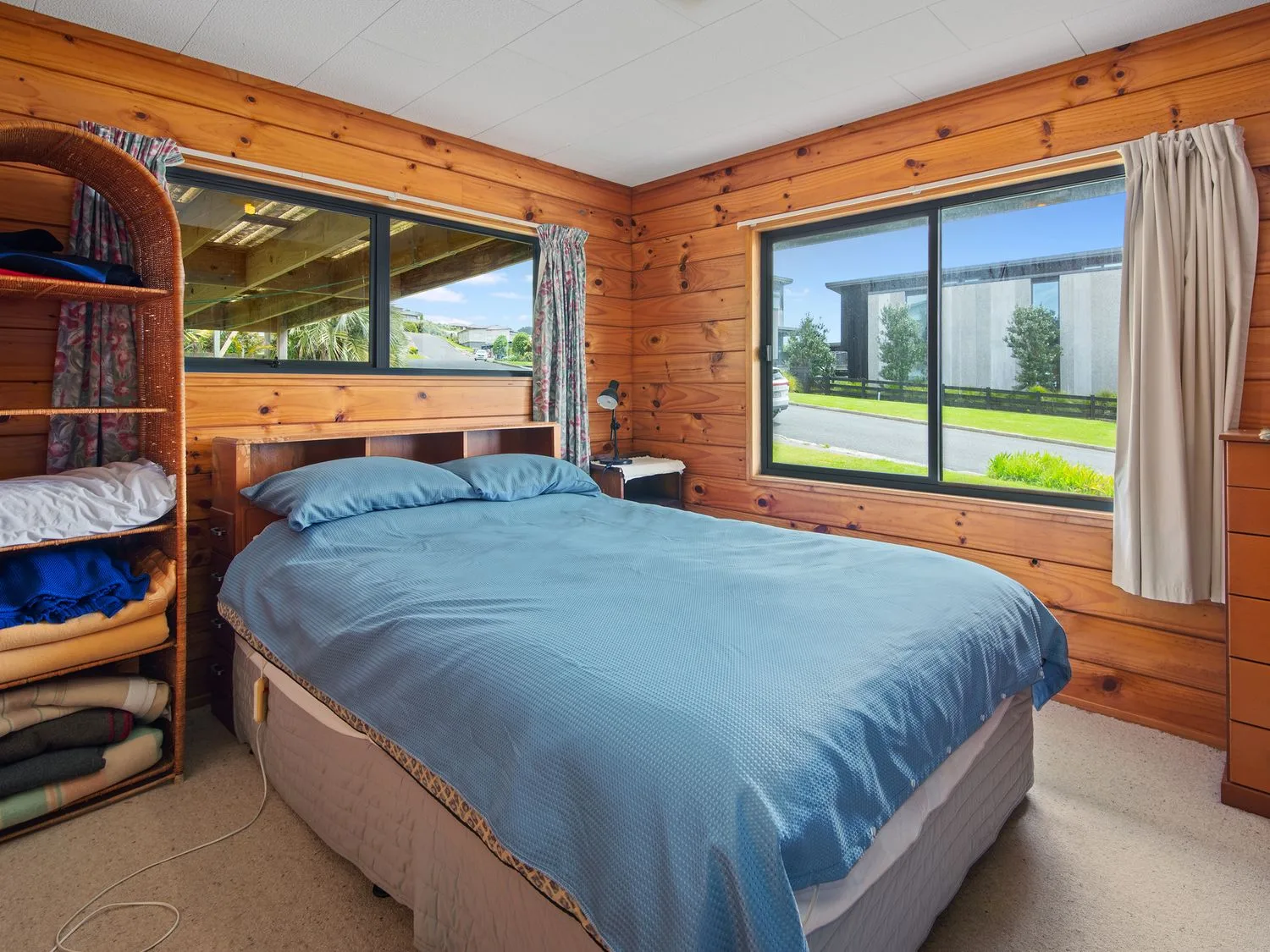 Un dormitorio con una cama doble cubierta con ropa de cama azul y paredes revestidas de madera.