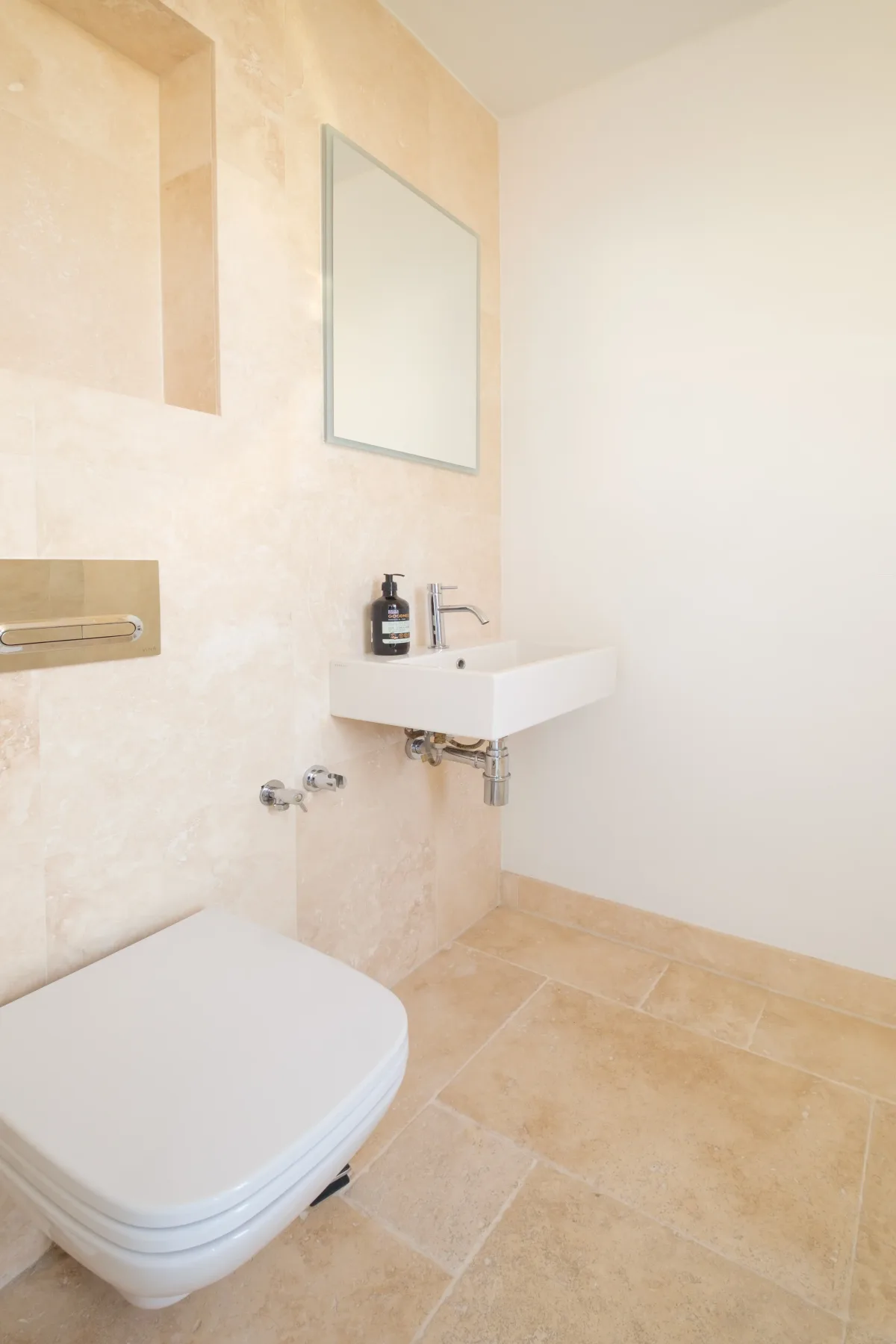 A bathroom with a wall-mounted sink and toilet.