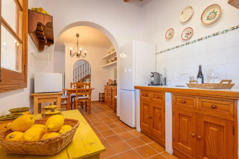 A rustic kitchen and dining area with wooden cabinets and a table of lemons.