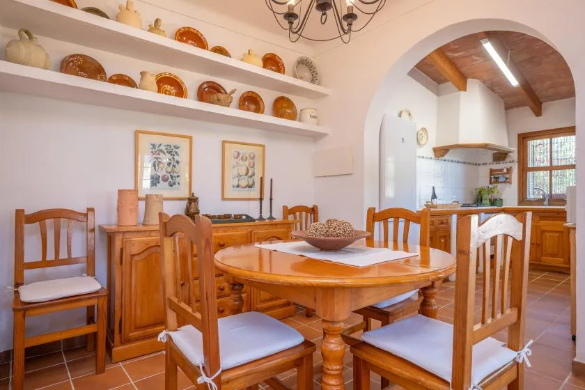 A dining room with a wooden table and chairs beside an arched kitchen opening.