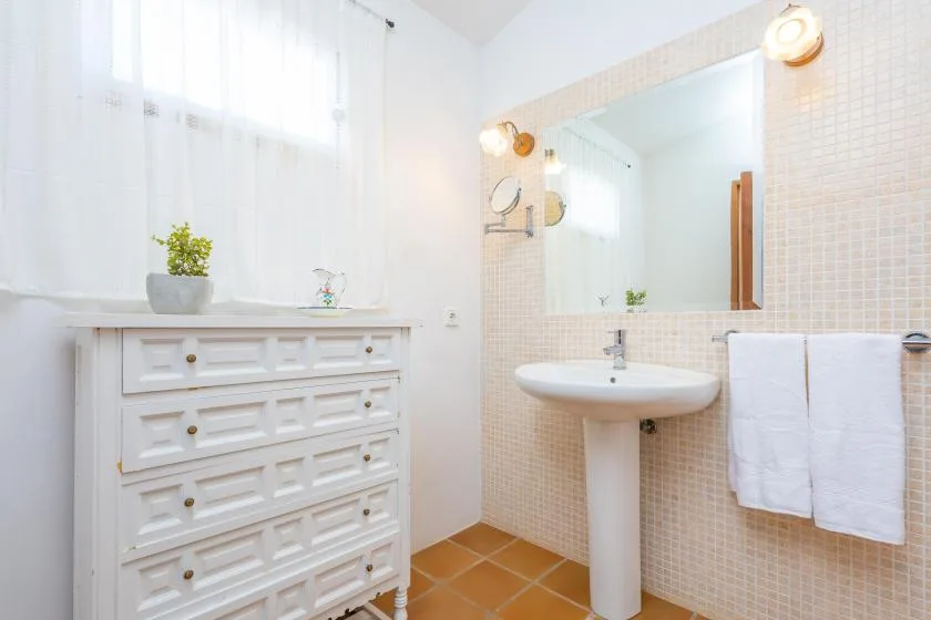 A bright bathroom with a sink, mirror, and white storage cabinet.