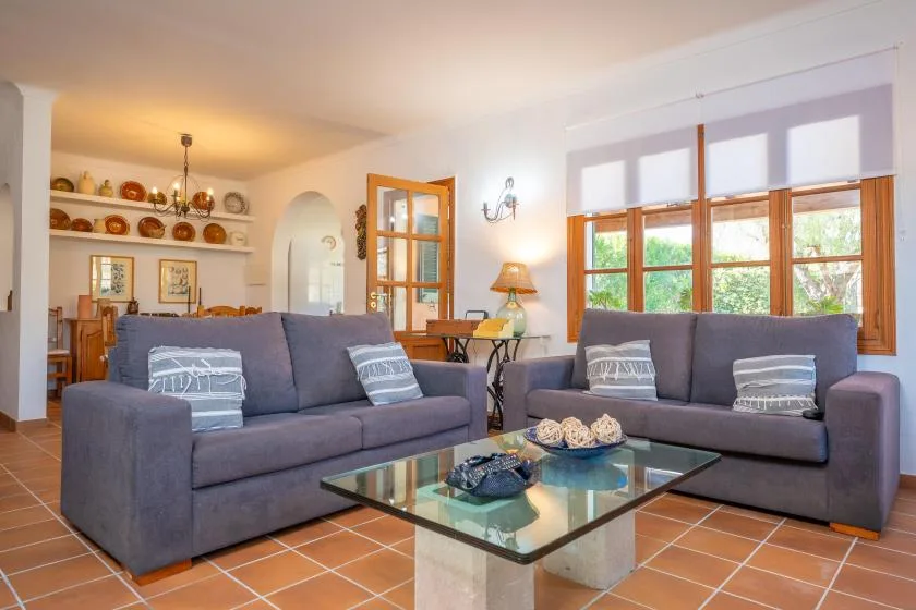 Living room with two sofas and a glass coffee table beside large windows.