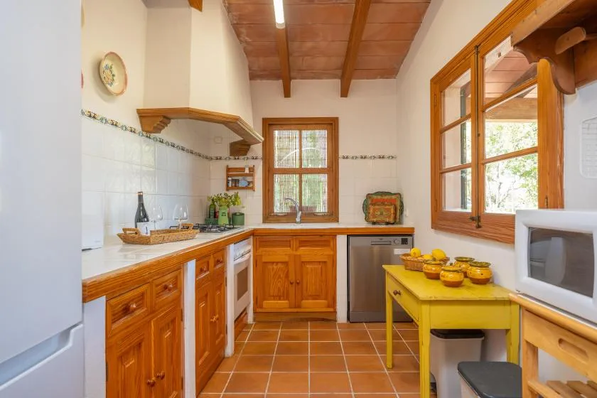 A bright kitchen with wooden cabinets, tiled counters, and a yellow table.