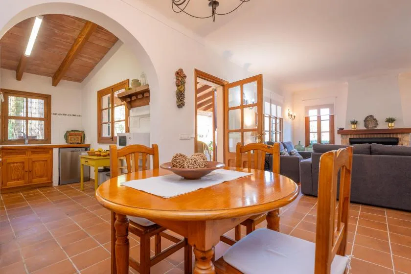 A dining area with a wooden table beside an open kitchen and living room.