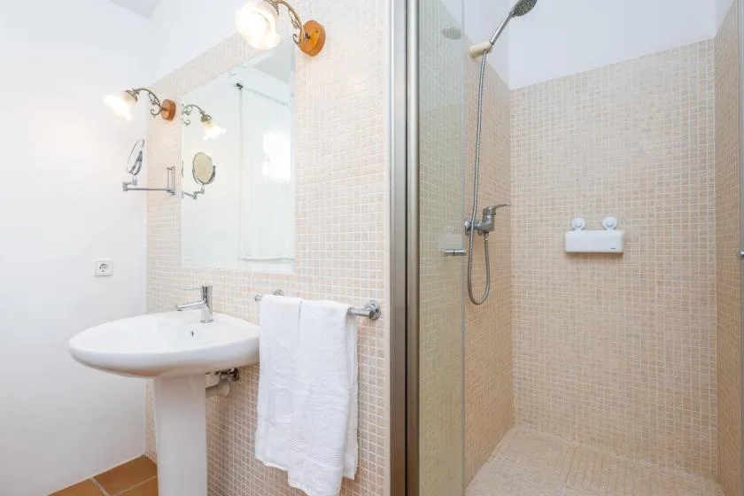 A bathroom with a pedestal sink and a tiled shower.