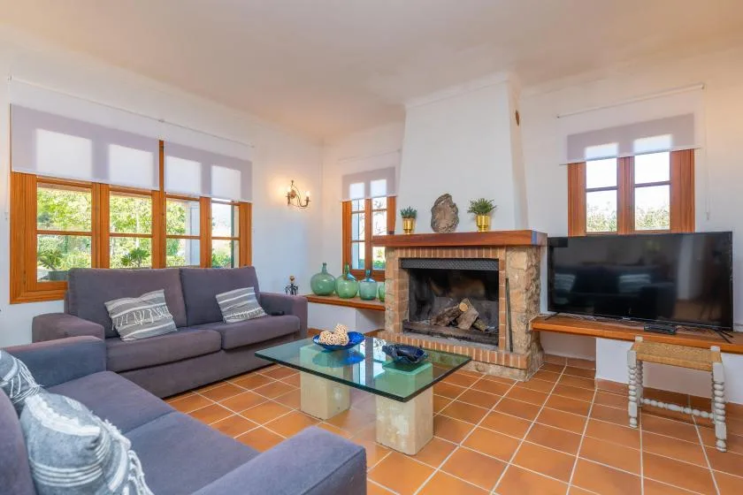 A living room with seating around a glass coffee table and a fireplace.