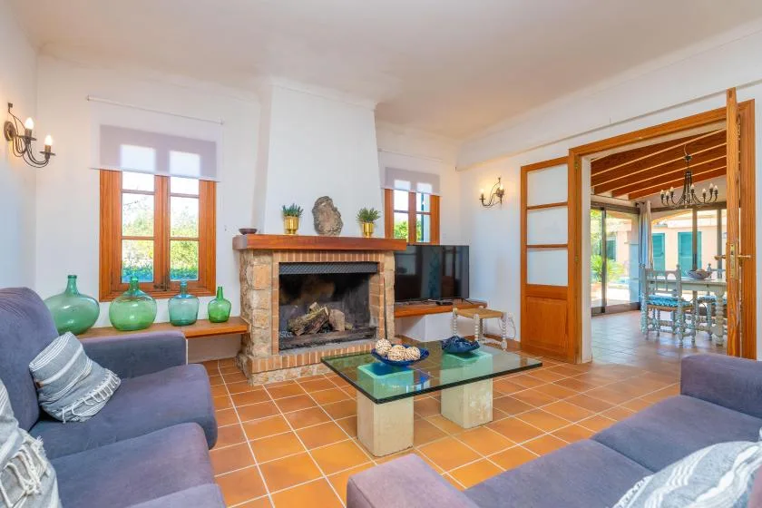 A living room with seating, a stone fireplace, and a glass coffee table.