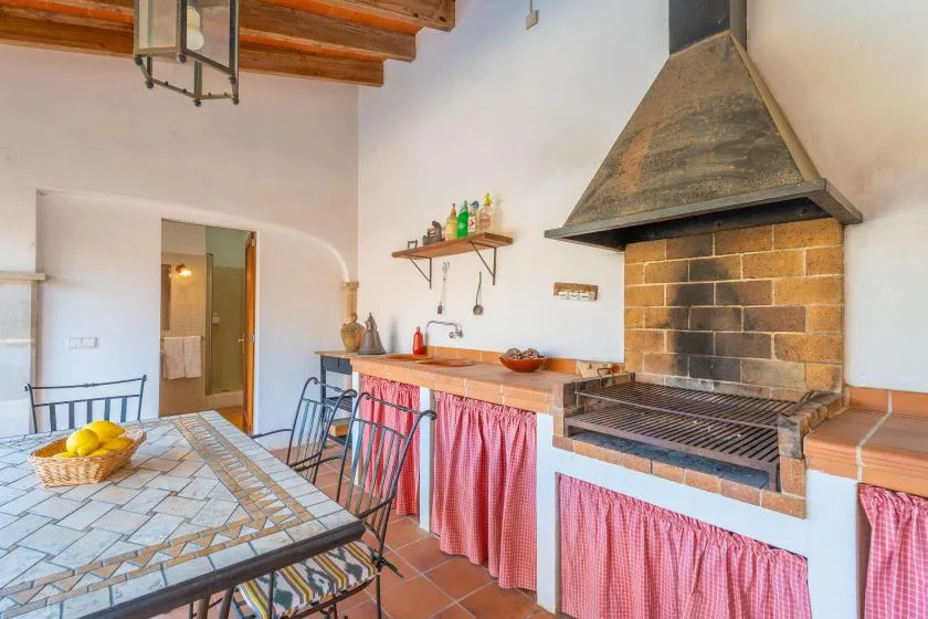 A kitchen with a large brick cooking range and a tiled dining table.