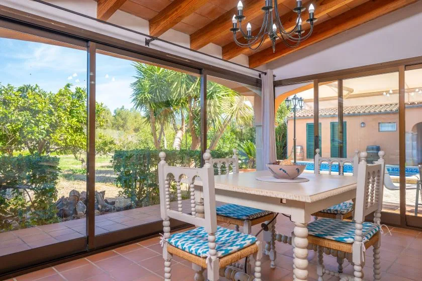 A dining area with a table and chairs beside large glass doors overlooking a garden.