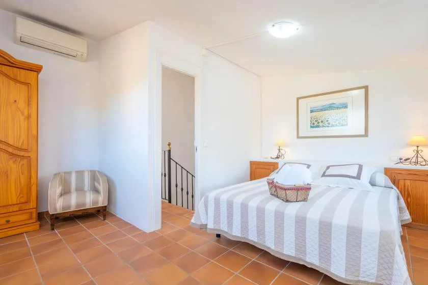 A bright bedroom with a striped bedspread and a framed picture on the wall.