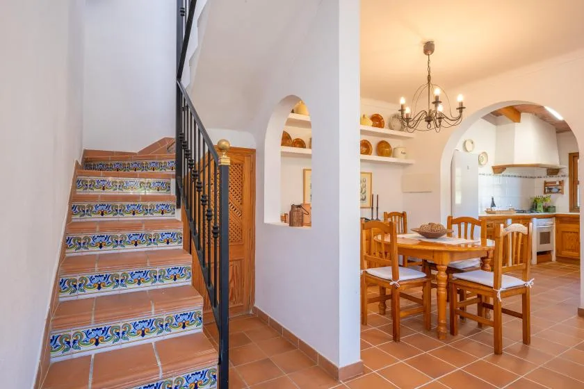 A tiled staircase opens onto a dining area with a wooden table and chairs.
