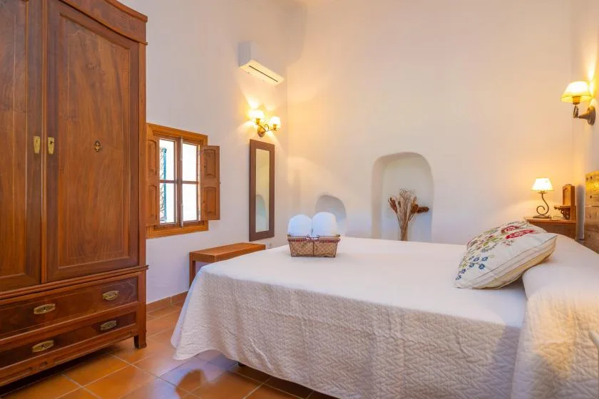 A bedroom with a neatly made bed and a wooden wardrobe.