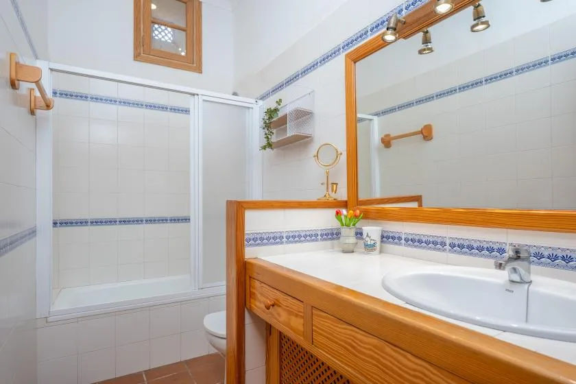 A tiled bathroom with a wooden vanity, sink, and shower.