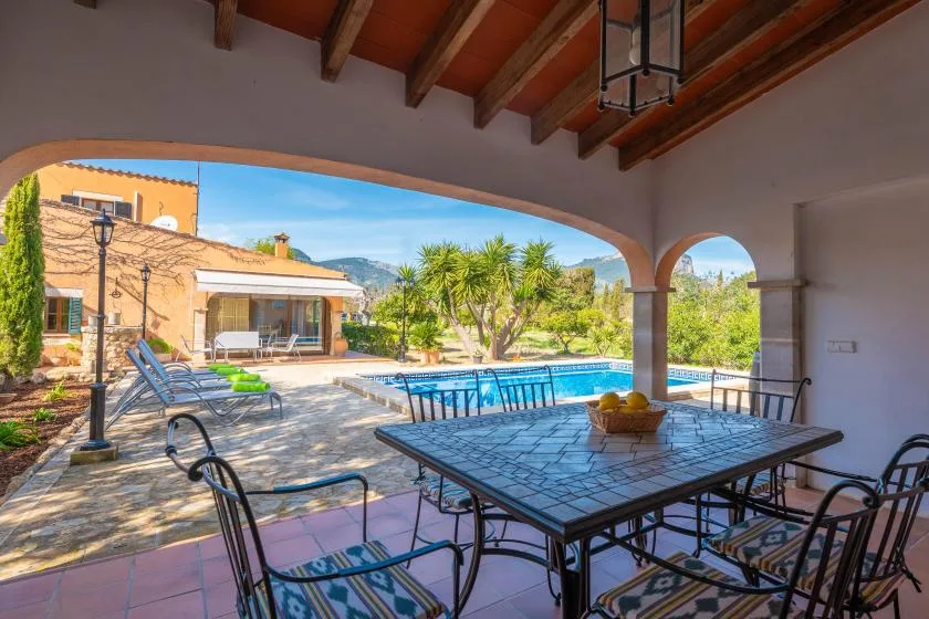 A covered patio dining area overlooks a swimming pool and landscaped courtyard.