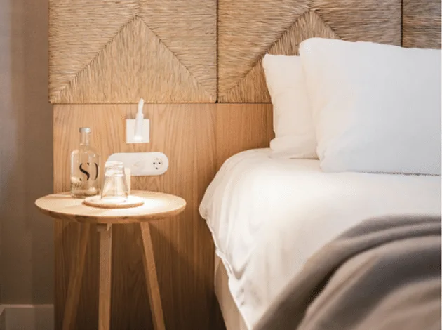 Cama hecha con una botella de agua del hotel