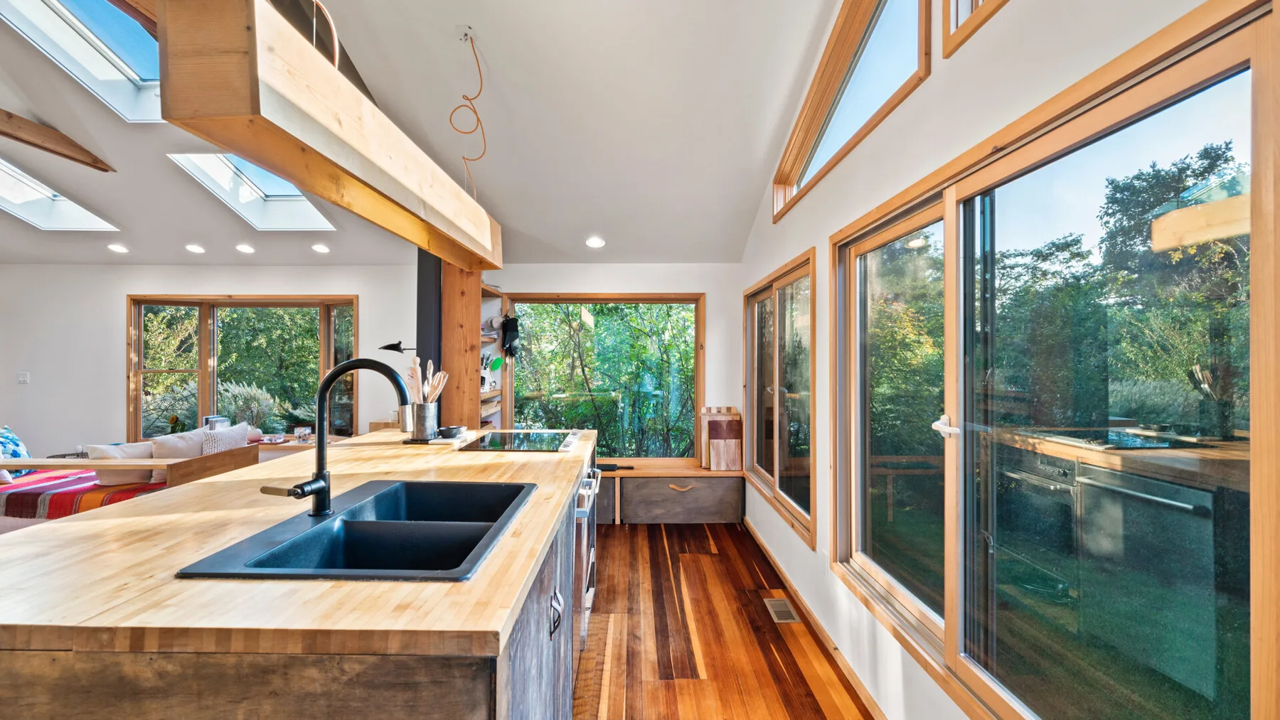 Una cocina luminosa con una isla central y grandes ventanas con vistas a los árboles.