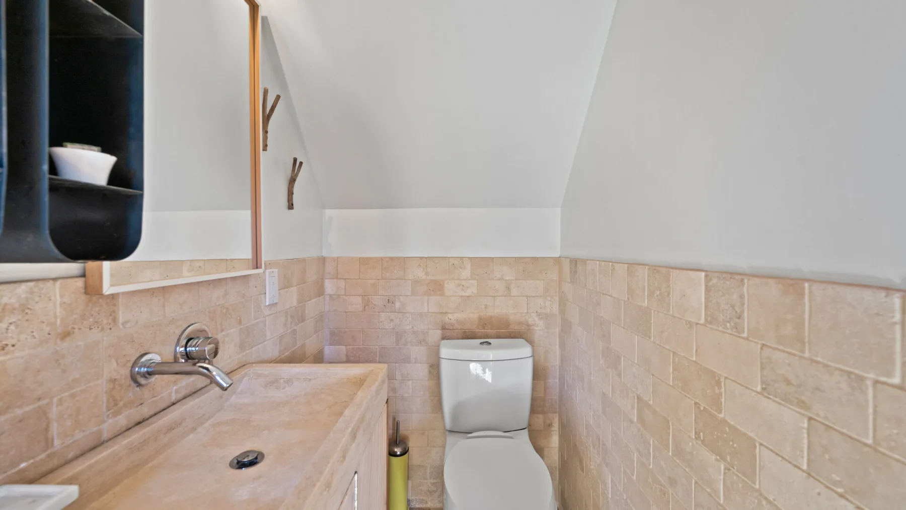 Un baño compacto con lavabo de piedra, inodoro y techo inclinado.