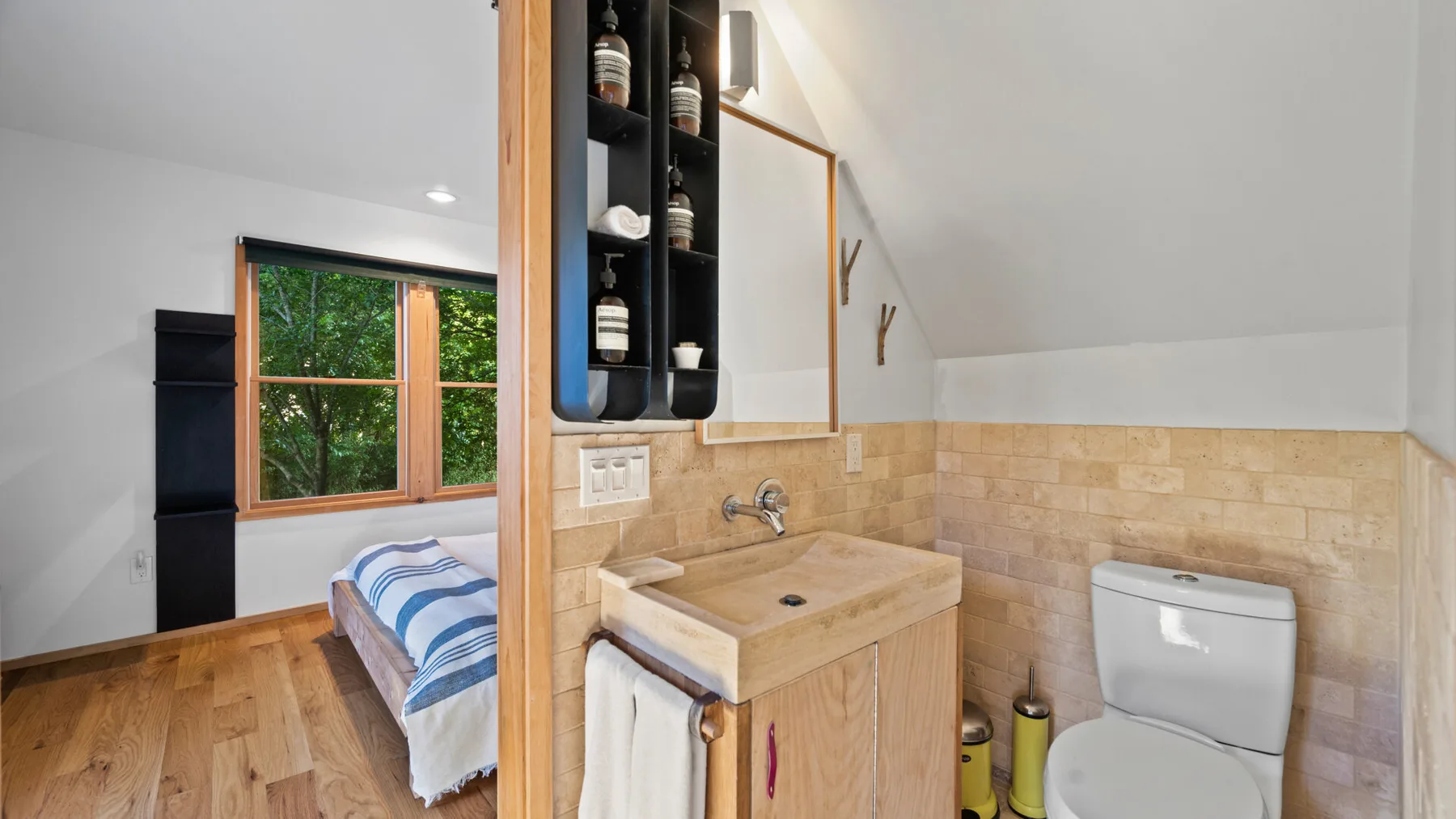Un lavabo y un inodoro están junto a una zona de descanso con ventana.
