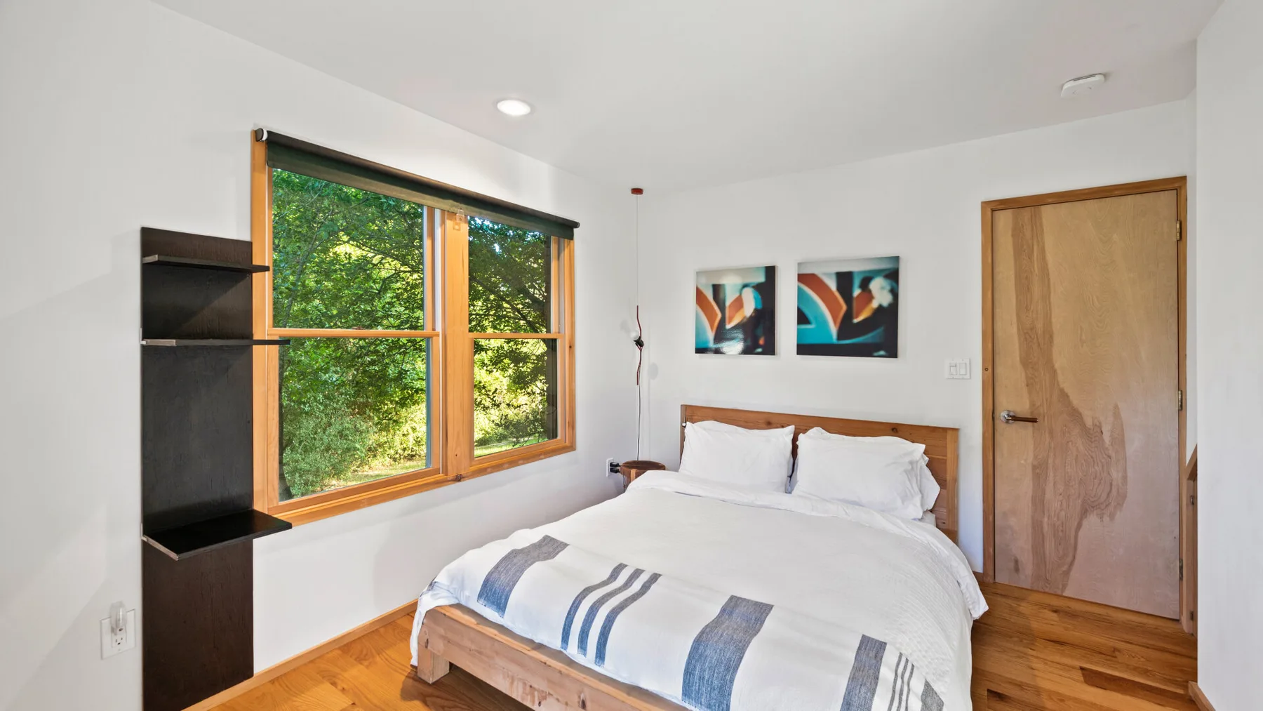 Un dormitorio con una cama doble, una ventana grande y una puerta de madera.