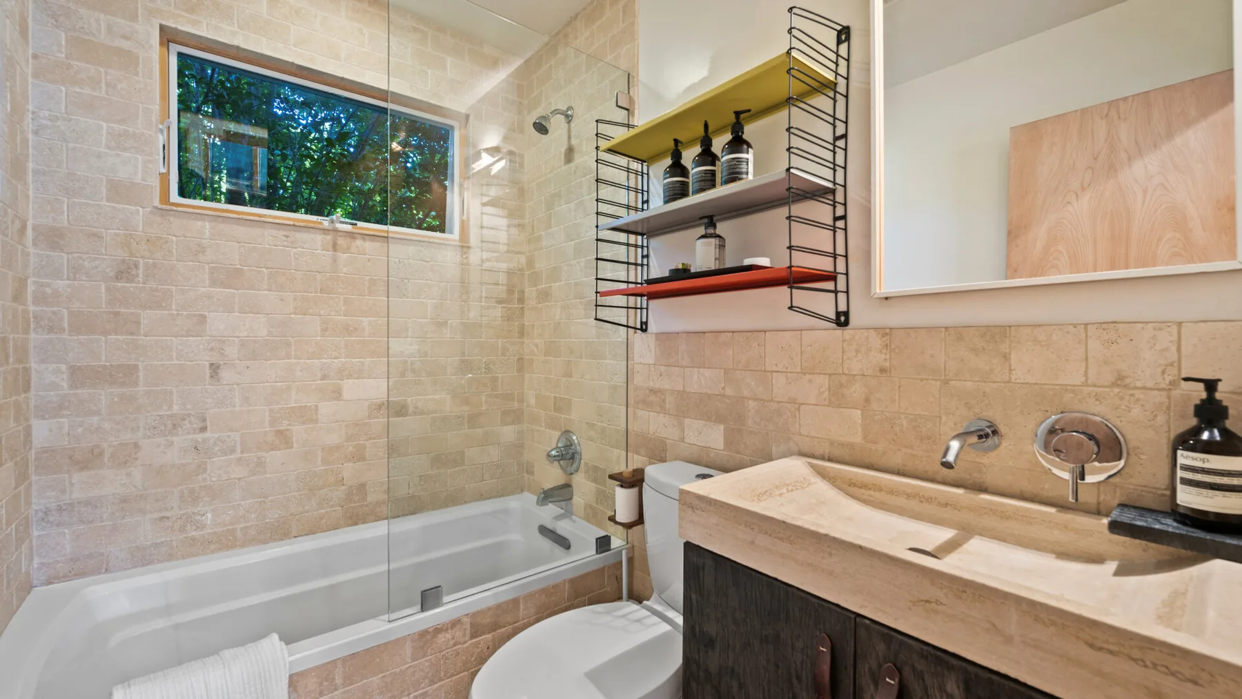 Un baño alicatado con bañera, mampara de vidrio y lavabo.