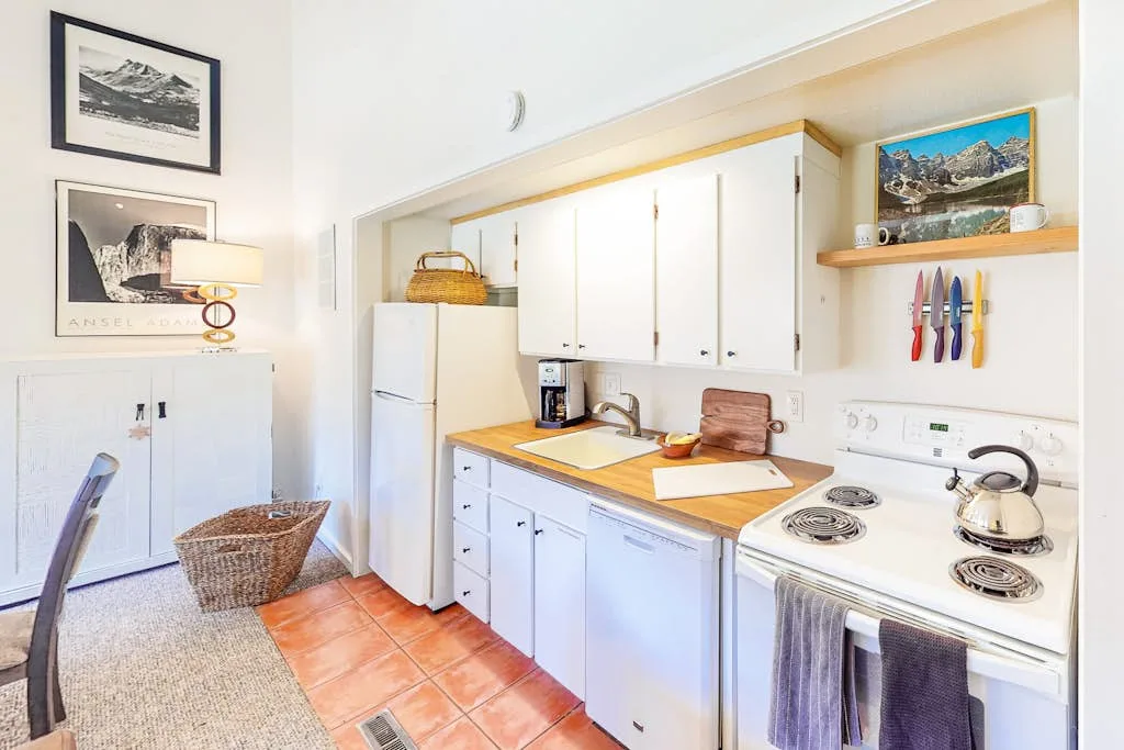 A bright kitchen with white cabinets, a refrigerator, and a stove.