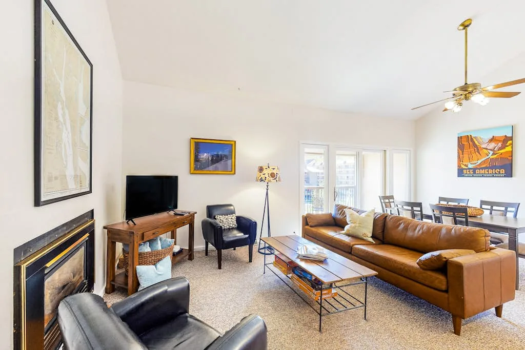 A bright living room with seating, a coffee table, and a television.