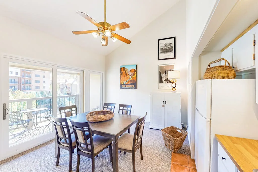 A dining area with a wooden table and chairs beside a bright balcony.