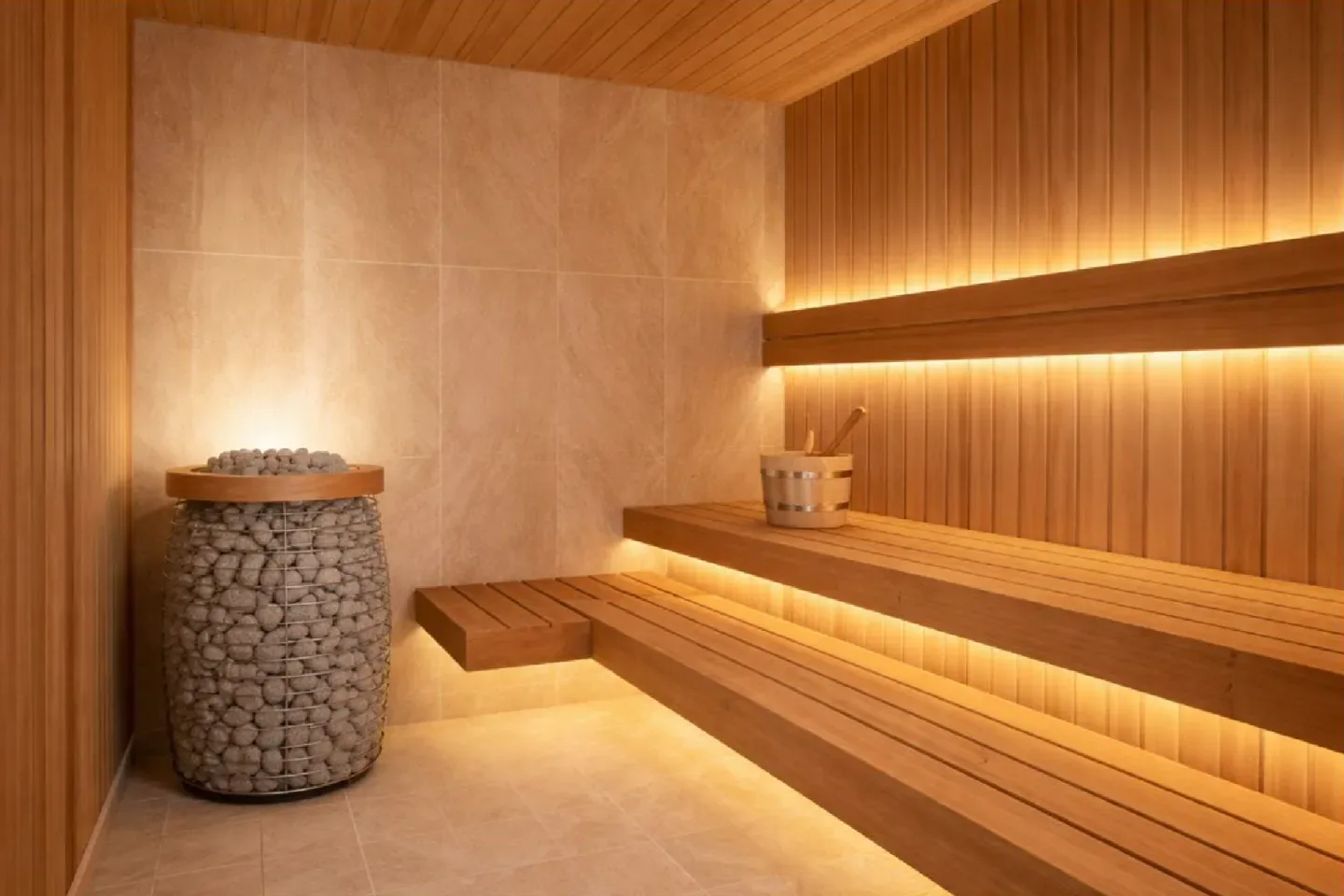 Wooden sauna interior with tiered benches and a stone heater.
