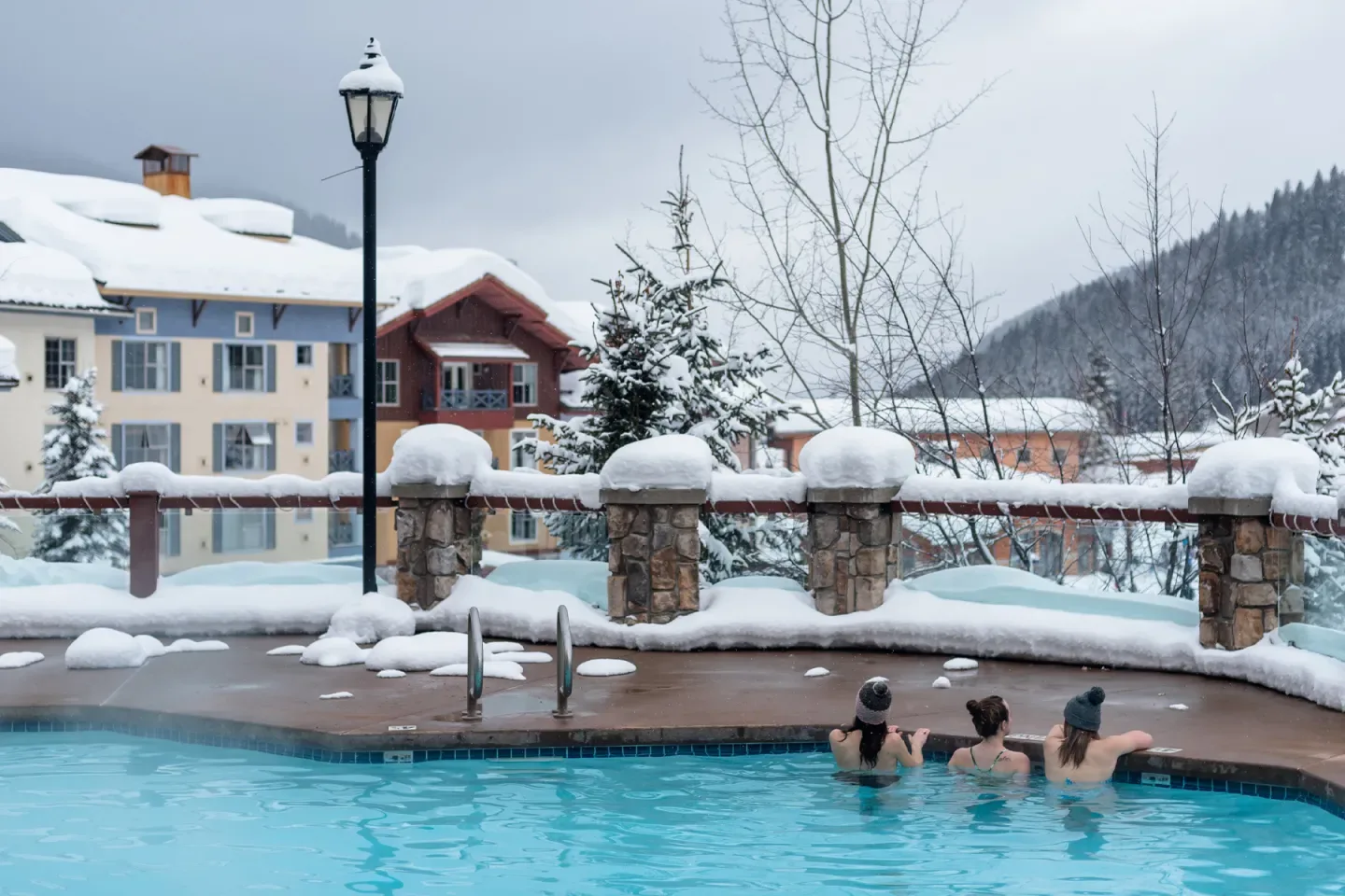 Guests in the outdoor pool beside chalet-style buildings.