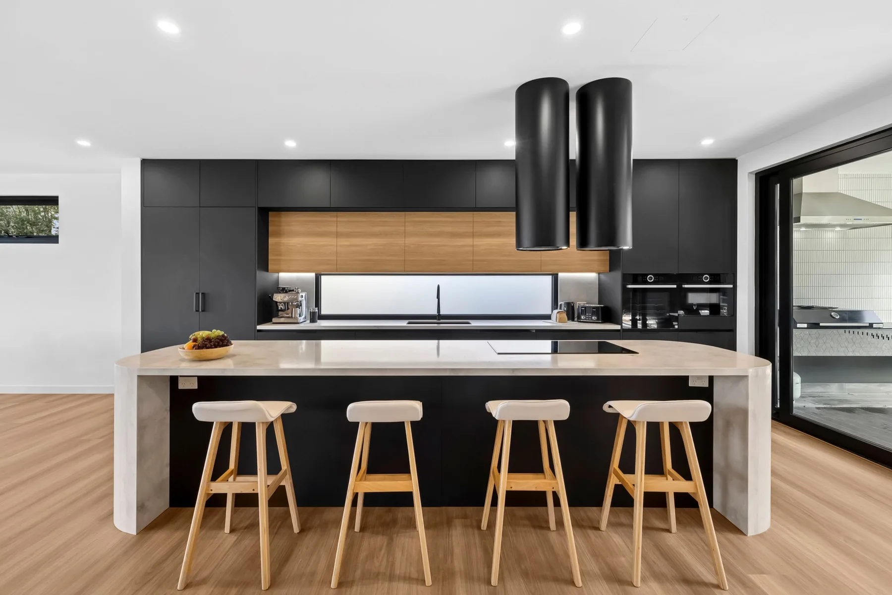 Una cocina moderna con una isla larga y taburetes de madera.