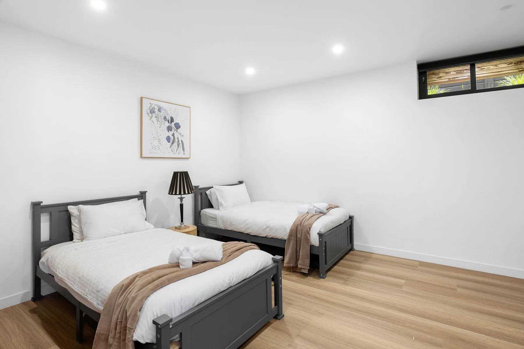 Un dormitorio luminoso con dos camas y una pequeña lámpara de noche.