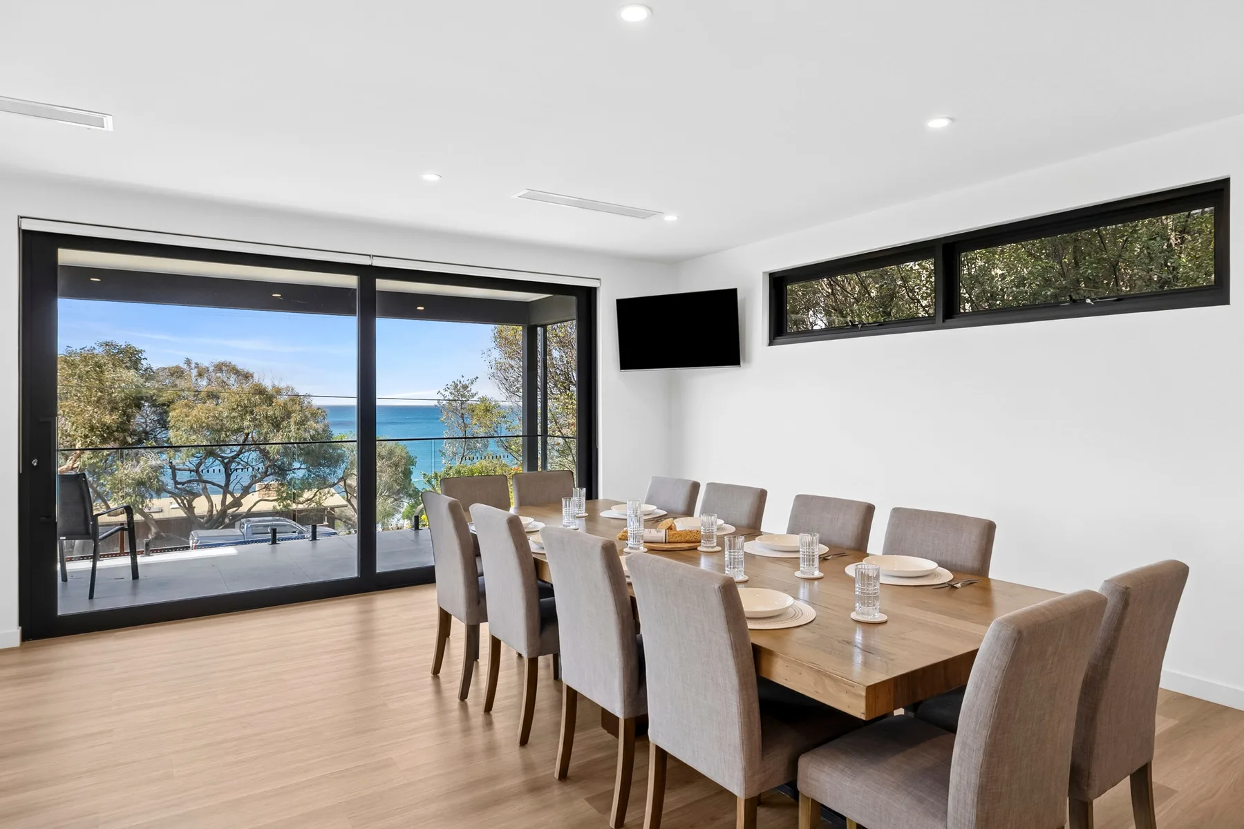 Comedor con una mesa larga y ventanas con vistas al agua.