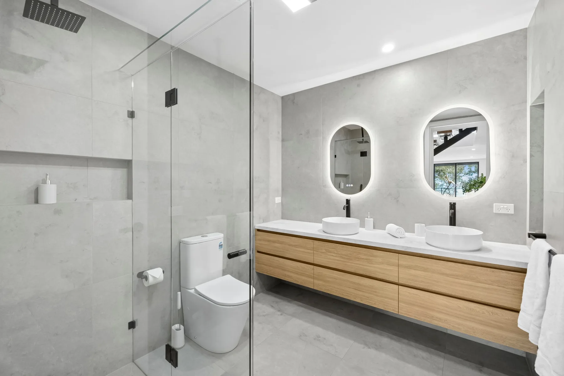 Un baño moderno con una ducha de vidrio y un mueble de lavabo largo.