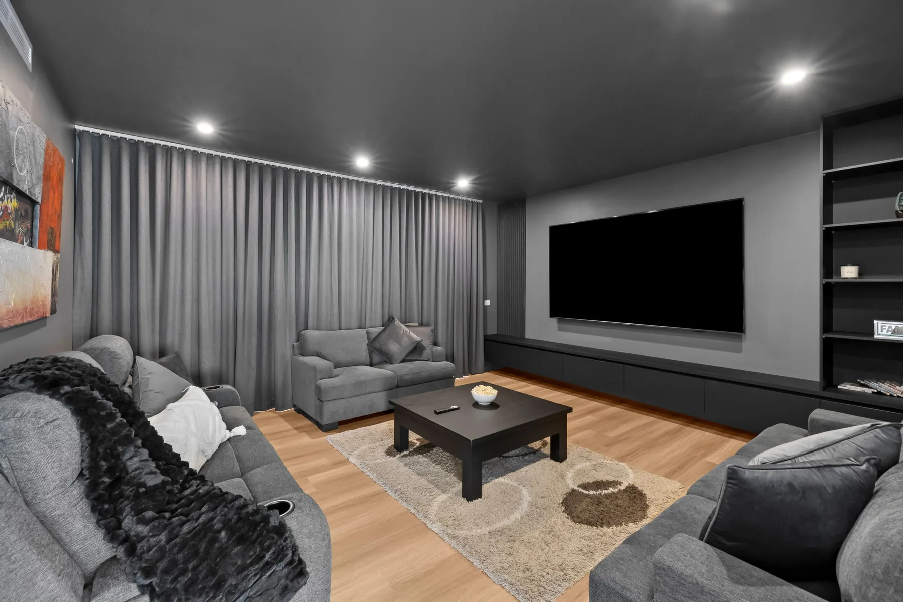 Una sala de estar con asientos alrededor de una mesa de centro y un televisor grande.