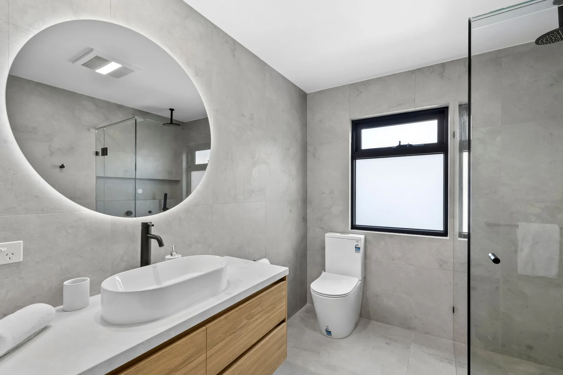 Un baño moderno con lavabo, inodoro y ducha de vidrio.