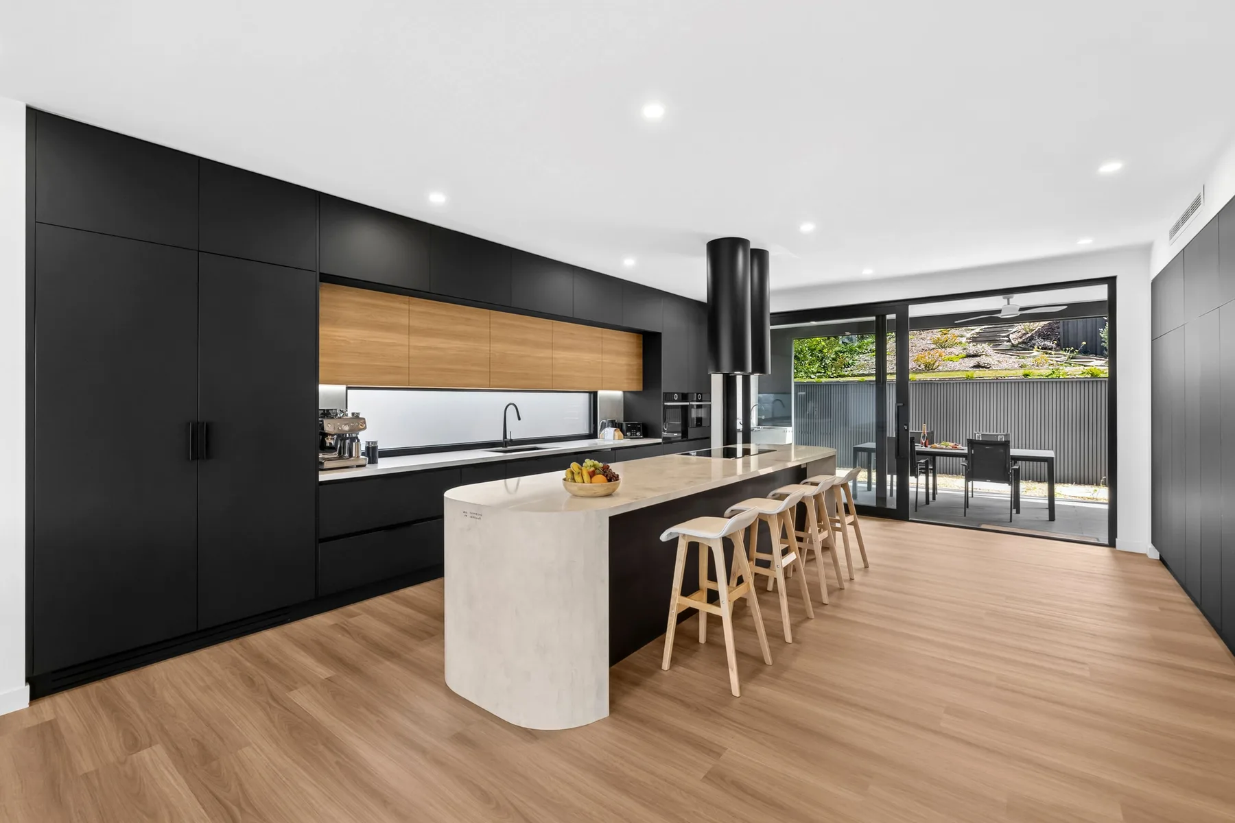 Una cocina moderna con una isla larga y taburetes junto a puertas de vidrio.