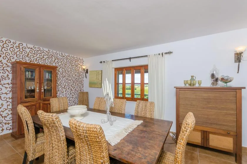 A dining room with a wooden table and woven seating beside a patterned wall.