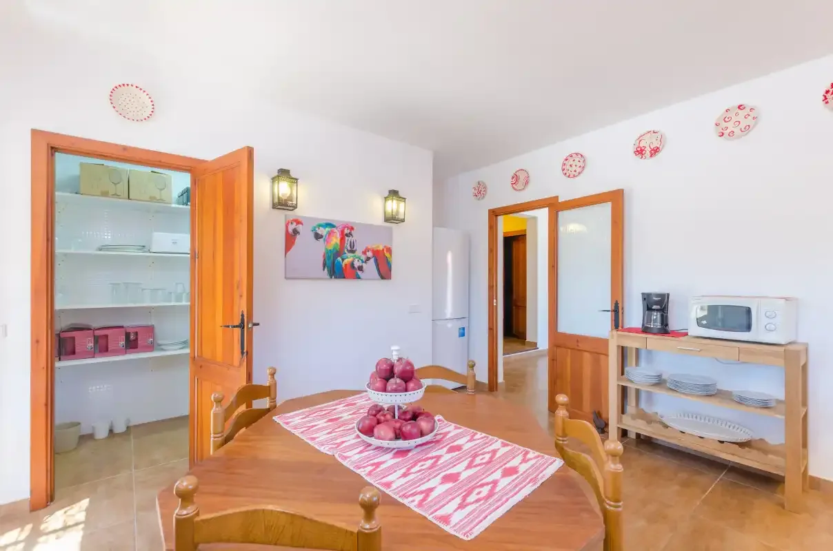 A bright dining room with a wooden table and colorful wall decorations.