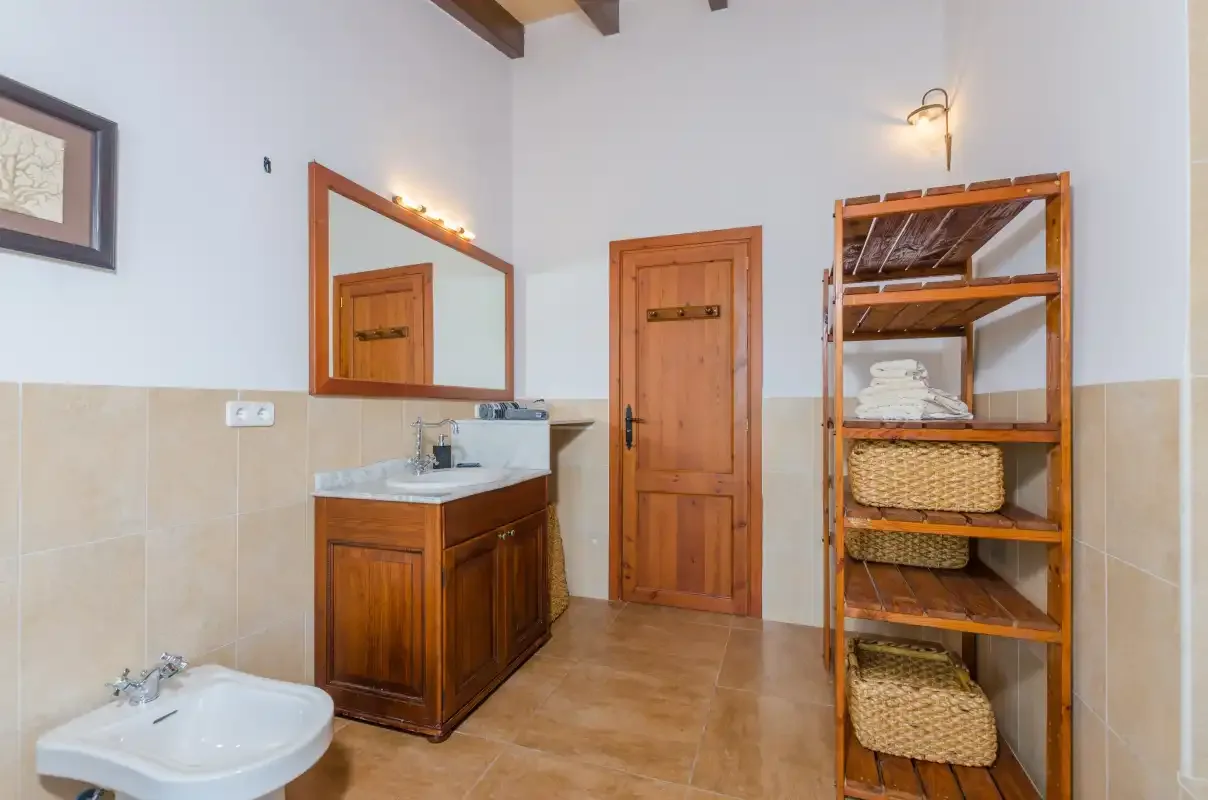 A bathroom with a wooden vanity, wall mirror, and open shelving.