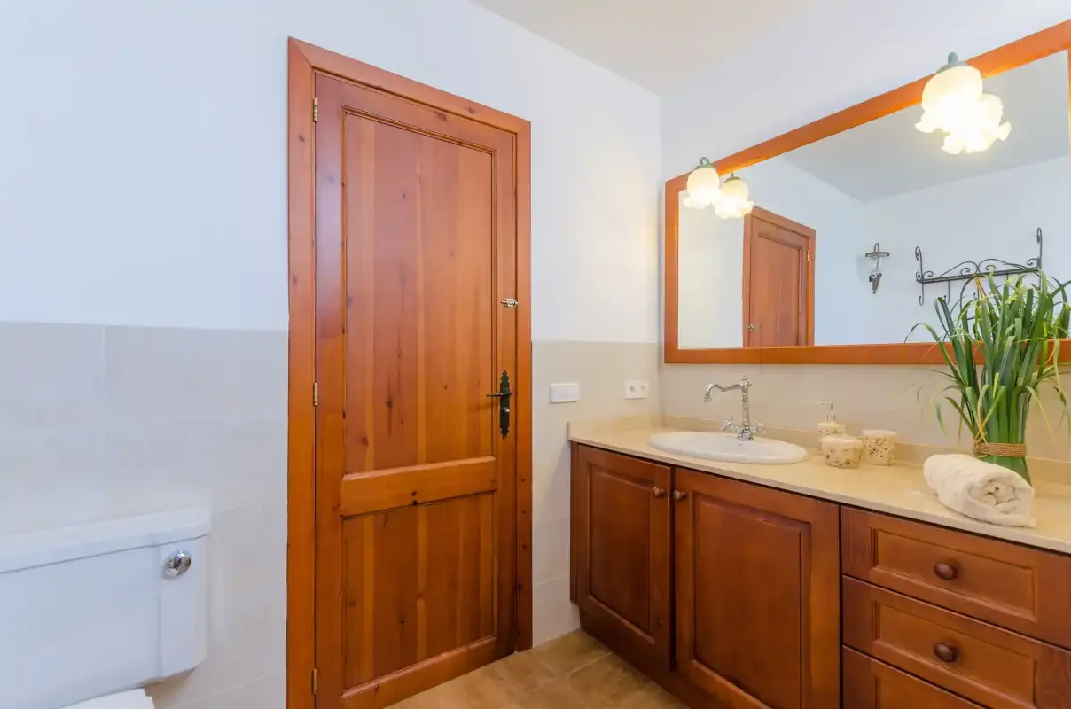 A bathroom with a wooden vanity, sink, and large mirror.